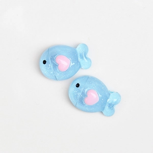 Détail de breloques poissons en résine bleue avec paillettes et cœur rose pour DIY