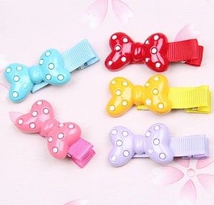 Detail of five polka dot resin bows hair clips in red yellow pink blue and purple colors