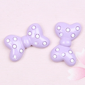 Close-up of light purple resin bow charms with white polka dots for DIY crafts