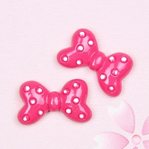 Close-up of hot pink resin bow accessories with white polka dots for DIY crafts