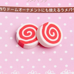 Macro shot of two red and white spiral clay narutomaki slices for DIY craft and phone cases