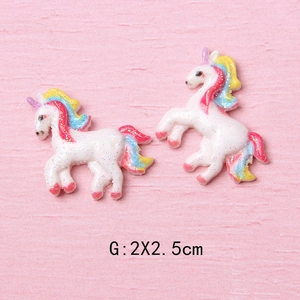 Detail of two glittery rainbow unicorn resin charms measuring 2x2.5cm for DIY crafts