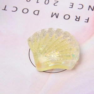 Macro-opname van schelpvormige harsbedel met glitterpailletten voor DIY telefoonhoesjes