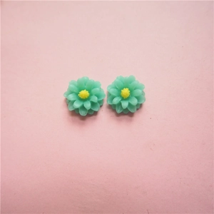 Macro view of mint green resin daisy charms with yellow stamen for DIY jewelry making