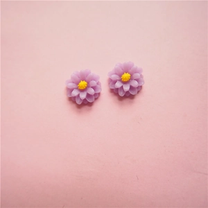 Flat lay of small light purple resin daisy flower charms for DIY jewelry and crafts