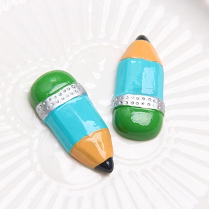 Detailed macro of vibrant resin pencil charms with glitter accents on a white tray