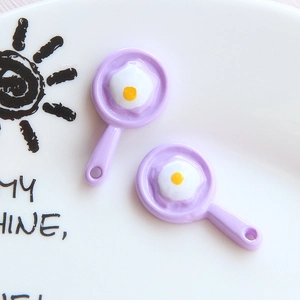 Detail of purple resin frying pan charms with egg design and integrated hanging loops