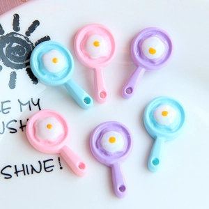 Macro detail of miniature resin frying pan charms with fried egg design in pastel colors