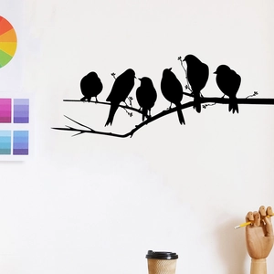 Close-up of bird branch wall stickers with black silhouette birds in a minimalist room