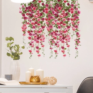 Detail view of pink and red hanging rose vines against a wall in a cozy room