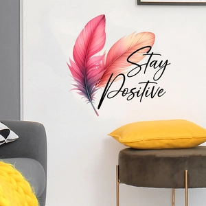 Detail view of the colorful feather wall decal with Stay Positive text on a white wall