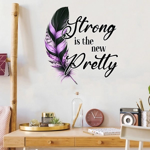 Detail view of feather wall sticker with 'Strong is the new Pretty' text on a white wall