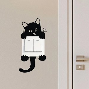 Gros plan du sticker mural chat noir entourant un interrupteur blanc sur le mur