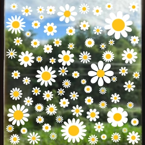 Macro detail of waterproof white and yellow daisy stickers on a clear glass window surface
