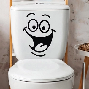Close-up of a cartoon smile toilet decal on a white ceramic tank in a cozy bathroom