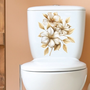 Close-up of golden flower and butterfly stickers on a white ceramic toilet tank