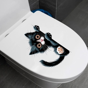 Detail of funny peeking black cat wall sticker on a white bathroom toilet lid