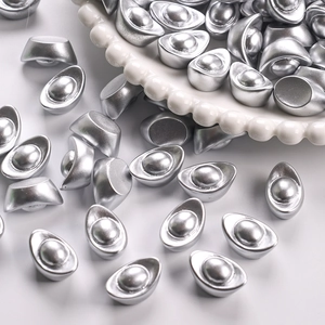 Close-up of numerous mini silver resin ingots scattered on a white embossed ceramic plate