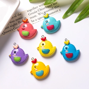 Macro shot of colorful resin cartoon bird charms with heart decor and metal loops