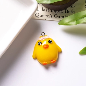 Detailed macro view of a cute yellow resin chick pendant with a pink bow and metal hook