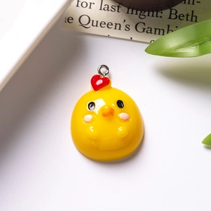 Detailed view of yellow resin chick charm with red heart and silver metal loop