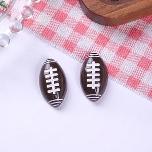 Macro detail of two resin American football charms with brown finish and white stitching