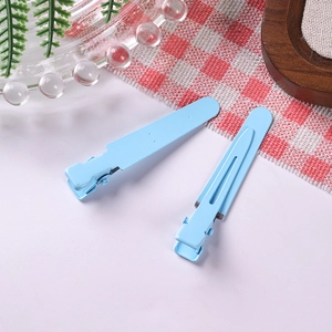 Detail of two matte sky blue metal hair clips on a white background with a rustic setting