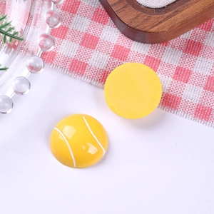 Macro shot of yellow resin tennis ball charms with textured stitch for DIY crafts
