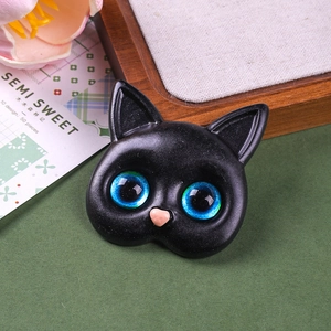 Detailed view of resin black cat head accessory with striking blue-green glass eyes