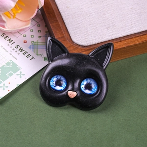 Detailed macro shot of a black resin cat accessory with vibrant blue galaxy glass eyes