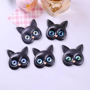 Macro detail of resin cat charms with colorful glass eyes and pink heart nose for DIY crafts