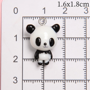 Macro detail of mini resin panda pendant with metal ring on a metric grid scale
