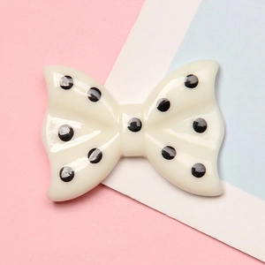 Cute resin polka dot bow accessory for DIY phone cases and hair clips on pastel background