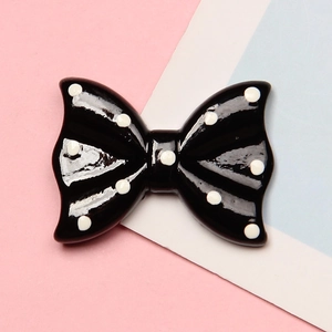 Detailed close-up of a black resin bow tie patch with white polka dots for DIY crafts