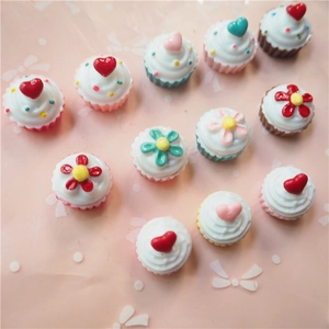 Flat lay of colorful resin cupcake charms with hearts and flowers for DIY crafts