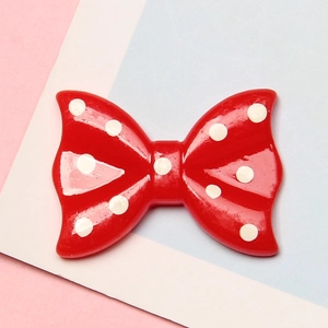 Detailed view of red resin bow with white polka dots for DIY hair clip and crafts