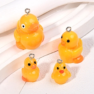 Macro detail of four yellow resin 3D duck pendants with silver metal loops for DIY crafts
