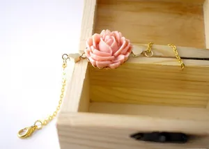 Detail of pink resin rose charm with gold heart accents on a delicate link chain
