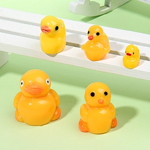 Detailed view of five mini resin yellow ducks in varying sizes on a white miniature bench
