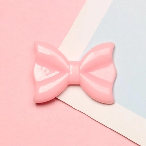 Detailed view of a pink resin polka dot bow accessory for DIY craft hair clips and cases