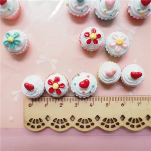 Detailed view of 15mm resin heart cupcake cabochons with ruler for size measurement