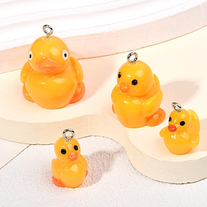Detailed view of four assorted resin yellow duck charms with metal loops on white stairs