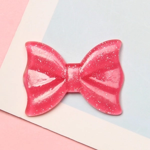 Macro detail of a sparkling pink resin bow charm with silver glitter for DIY crafts