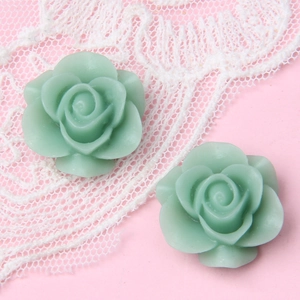 Makroaufnahme von zwei hellgrünen Harzrosen auf elegantem weißem Spitzenhintergrund