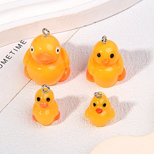 Close-up of four mini yellow resin duck pendants for DIY jewelry and phone charms