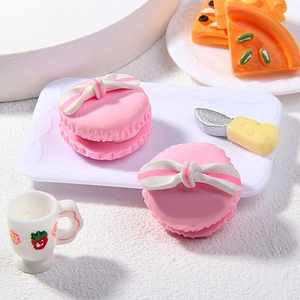 Makro-Detail eines 25mm rosa Macaron-Anhängers aus Ton mit Schleife auf einem Tablett