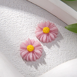 Vista macro de dijes de margaritas de resina rosa de 12mm para joyas DIY y fundas móvil