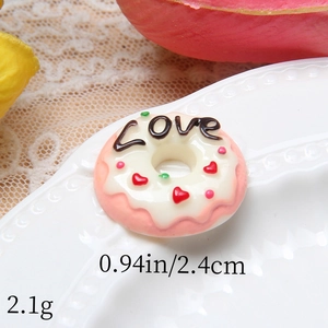 Macro shot of large pink resin donut cabochon with white cream and LOVE lettering