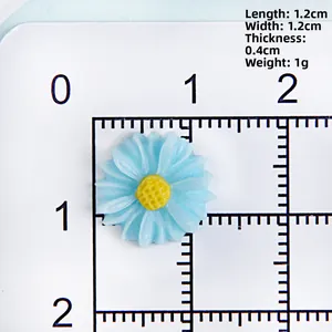 Detailed view of a 12mm blue resin daisy accessory with yellow pistil on a measuring scale
