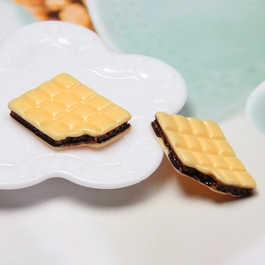Macro shot of two realistic 3D chocolate sandwich biscuit resin charms in a white dish